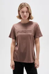 Remera de manga corta color marrón con cuello redondo y estampado frontal con la frase "Who are you when no one is watching?".