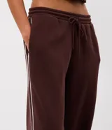 Pantalón de buzo de corte recto, color marrón, con cintura elástica y franjas laterales en contraste. Confeccionado en tejido de algodón y poliéster con interior de felpa.