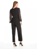 Enterito de seda fría color negro, con escote en V cruzado y cintura elástica con lazo lateral. Presenta mangas largas de gasa transparente con puños elásticos fruncidos y pantalón de corte recto al tobillo.