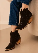 Bota corta estilo western confeccionada en gamuza color marrón oscuro, con taco de madera de diseño geométrico y puntera reforzada con detalle metálico.
