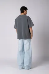 Remeron de corte oversized con cuello redondo y mangas cortas. Presenta un acabado de tela con efecto desgastado y costuras visibles en los bordes, con una etiqueta pequeña en el lateral inferior.