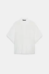 Camisa de corte fluido confeccionada en mezcla de modal, con cuello solapa, manga corta y bolsillo de plastrón en el delantero. Presenta cierre frontal con botones ocultos por tapeta y bajo con aberturas laterales.