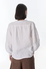 Camisa celeste de lino con botones, mangas largas abullonadas y detalles de crochet en el frente y los puños.