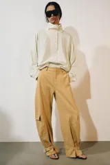 Chaqueta de nylon color crudo, con cuello alto, mangas largas, bolsillos delanteros, bajo abullonado con elástico y cierre frontal con botones forrados.