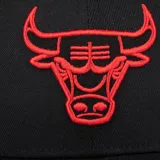 Gorra negra con diseño estructurado, visera curva y el logo bordado de los Chicago Bulls en color rojo en la parte frontal.