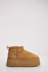 Bota corta tipo ugg en color camel, con plataforma alta y suela dentada. Presenta un diseño de gamuza con interior forrado y tirador en la parte trasera.
