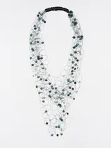 Collar de cuentas azules y celestes con hilos plateados y cierre de cordón negro.