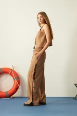 Pantalón marrón de corte recto, con cintura elastizada y cordón ajustable. Presenta mostacillas decorativas en los laterales.