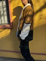 Campera marrón con mangas de corderito color crema y parte inferior de cuero sintético negro con textura de cocodrilo.