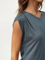 Remera blanca de corte clásico con cuello redondo y mangas cortas con detalle de hombreras.
