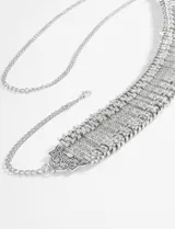 Cinturón plateado de estilo tribal o étnico, compuesto por múltiples tiras metálicas con patrones grabados y un cierre de cadena ajustable con un dije ornamental en el extremo.