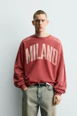 Sudadera de corte boxy fit con cuello redondo y manga larga. Presenta un diseño con efecto lavado y estampado frontal con la palabra Milano en tipografía universitaria a contraste.