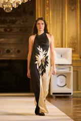 Vestido largo halter con diseño bicolor en negro y beige, con espalda abierta y gran aplicación floral bordada en el delantero.