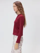 Remera de manga larga con cuello a la base, confeccionada en tejido de punto acanalado color beige. Presenta un logo bordado en el centro del pecho.