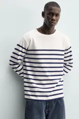 Remera de manga larga de corte relaxed fit, con diseño a rayas horizontales azul marino sobre base blanca y cuello redondo.