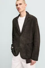 Blazer de corte relajado confeccionada en piel con acabado de ante. Presenta cuello con solapas de muesca, cierre frontal de dos botones, mangas largas y bolsillos de plastrón en la cadera. El diseño no posee forro interior y cuenta con aberturas en la parte trasera.