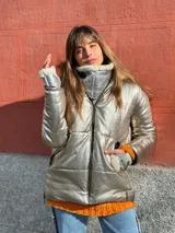 Campera puffer color plateado metalizado, con cierre frontal y cuello alto con detalles de corderito blanco.
