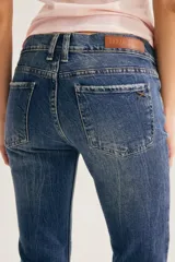 Pantalón jean de corte bootcut, color azul con lavado y efecto desgastado, de tiro medio y con bordes deshilachados en el bajo.