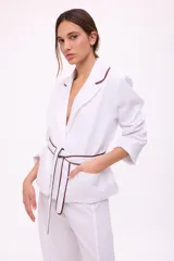 Blazer blanco con solapas con borde marrón, corte recto, mangas 3/4 y cinturón marrón.