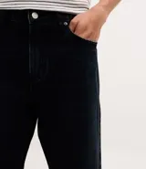 Pantalón de corte recto confeccionado en denim de algodón, con cintura tradicional y cierre de cremallera. Presenta un lavado oscuro que aporta un estilo versátil y urbano.