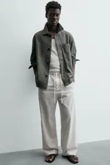Pantalón de corte regular fit confeccionado en mezcla de algodón y lino. Presenta cintura elástica con cordón ajustable, cierre frontal con cremallera y botón, bolsillos laterales y bolsillo trasero de vivo con botón.