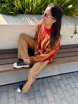 Sweater de punto con cuello alto, diseño geométrico con rayas diagonales en tonos naranja, marrón y blanco.