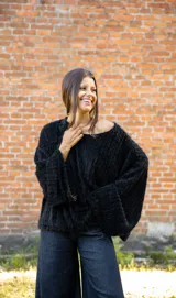 Buzo de textura tipo peluche en color negro, con diseño oversize, cuello amplio y mangas largas acampanadas.