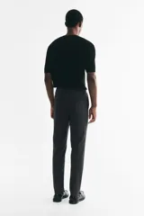 Pantalón sastrero gris oscuro con corte slim fit, pliegues frontales y raya marcada en las piernas. Cuenta con cierre de botón y bolsillos laterales.