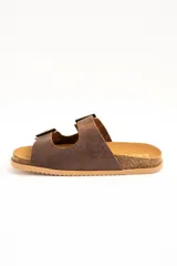 Sandalias de cuero marrón, con dos tiras anchas ajustables mediante hebillas metálicas doradas. Cuenta con una suela de corcho y base dentada.