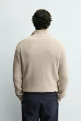 Jersey de punto perlado en color azul marino, con cuello perkins y cierre frontal de cremallera. Presenta manga larga y acabados en rib en puños y bajo.