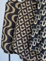 Poncho liviano de tejido de punto con diseño geométrico y ondulado en combinación de negro y dorado brillante.