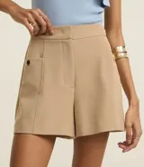 Short sastre de cintura alta con estructura definida, bolsillos laterales decorados con tachuelas metalizadas y recortes delanteros con costura aparente.