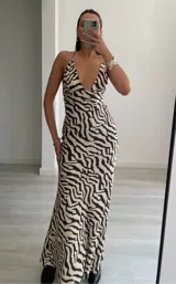 Vestido largo de satén con estampado de cebra, escote pronunciado en V y breteles finos que se atan al cuello.