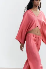 Pantalón de tiro alto color rosado, confeccionado en hilatura con lino, de pierna ancha y cintura elástica ajustable con cordones.