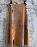 Falda midi confeccionada en cuero con diseño de paneles en tonos suela y beige. Presenta cintura ajustable y borde lateral irregular.
