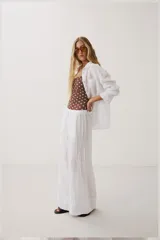 Camisa oversize blanca de manga larga con cuello camisero, bolsillo frontal en el pecho y cierre de botones.