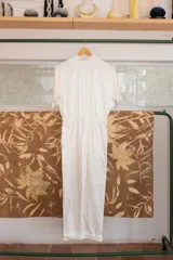 Mono blanco de gabardina de algodón, corte clásico con cierre frontal, pantalón largo con bolsillos, manga corta y cintura fruncida en la espalda.