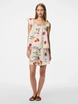 Top corto sin mangas con cuello cuadrado y tirantes ajustables con lazo. Presenta un estampado de frutas (fresas, limones/naranjas) y un patrón de cuadros en tonos verde, amarillo y rosa pálido. El borde del escote y el ruedo tienen un ribete ondulado verde.