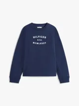 Buzo de felpa azul marino con cuello redondo, mangas largas y puños acanalados. Presenta un estampado frontal con el logo y letras de la marca Tommy Hilfiger en color blanco.