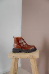 Borcego de cuero color suela con puntera redondeada, cierre mediante tiras de velcro y suela track de goma negra.