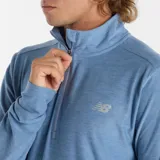 Buzo de hombre New Balance, modelo Space Dye 1/4 Zip MT41915DSW, color celeste jaspeado. Confeccionado en tejido polyknit con tecnología NB DRY de secado rápido. Cuenta con cierre de un cuarto, mangas largas con presillas para los pulgares y logo NB reflectante.