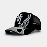 Gorra tipo trucker color negro con panel frontal bordado que presenta el logo 'LA' y diseño de llamas tribales en tonos gris y blanco. Cuenta con parte trasera de malla ajustable.