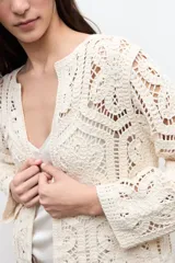Chaqueta tejida a crochet en color beige claro, de diseño abierto y manga larga con patrones geométricos calados.