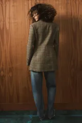 Blazer de corte entallado con estampado de cuadros, cuello solapa y cierre frontal cruzado con botones. Presenta mangas largas con detalle de abertura y botones en los puños, y forro interior a contraste.