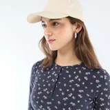 Camiseta de manga larga en tejido de punto acanalado color azul marino con estampado floral pequeño en tonos rosados. Presenta cuello redondo con cierre frontal de botones tipo henley.