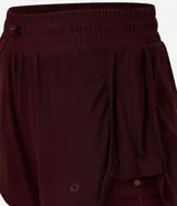 Bermuda deportiva femenina modelo runner, color bordó, con short interno incorporado. Presenta cintura elástica con cordón de ajuste y laterales con cordones ajustables. Confeccionada en tejido de tul con tecnología dry para mayor transpirabilidad.