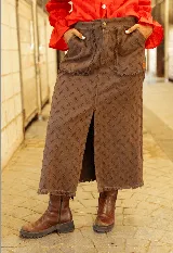 Pollera midi de jean color chocolate, con diseño de textura grabada, bolsillos frontales y tajo central delantero con ruedo desflecado.