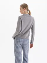 Sweater de punto gris con cuello polo y cierre frontal de tres botones, de manga larga y corte recto.