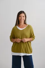 Sweater de tejido de punto color mostaza con diseño superpuesto, escote en V, mangas largas y detalle de vivo plateado en el borde de las mangas y el ruedo.