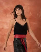 Top lencero negro con escote en V y detalles de encaje en el borde. Presenta breteles finos y un diseño fluido con acabado satinado.